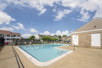 A large outdoor swimming pool with a sunny sky above.